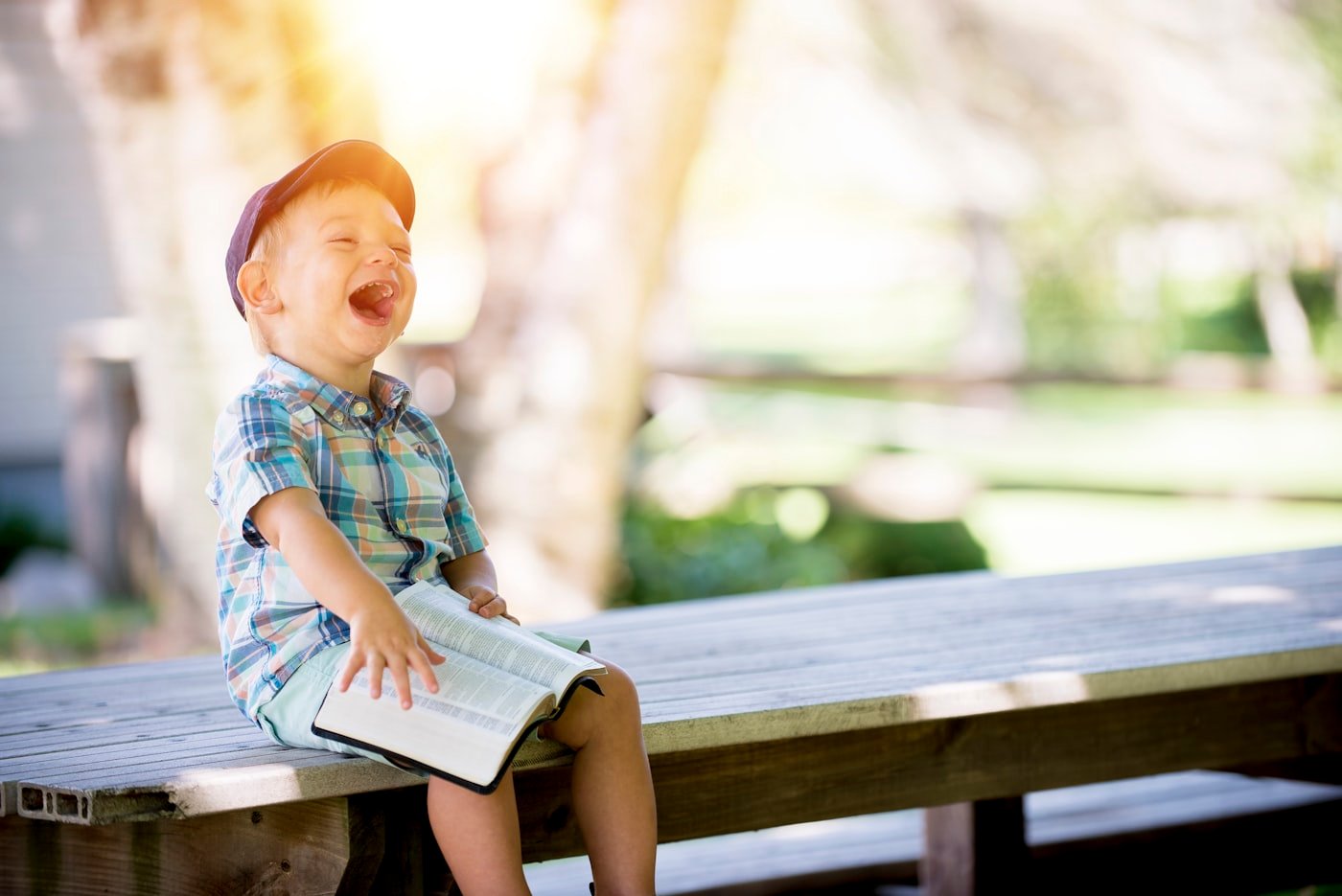 Bambino che ride all'aperto con un libro